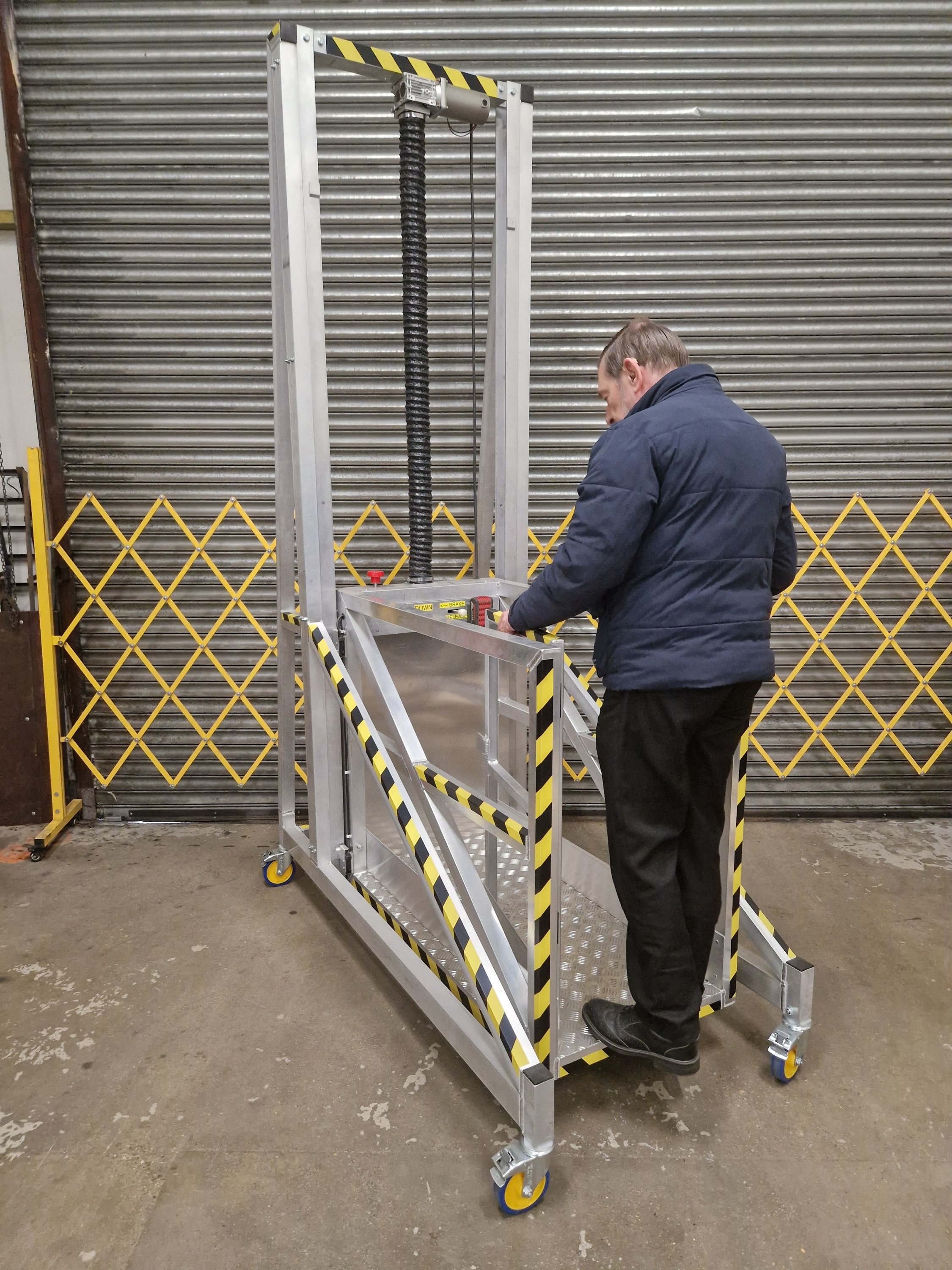 Industrial mobile access lift platform being operated from ground level for safe working at height and controlled elevated access.