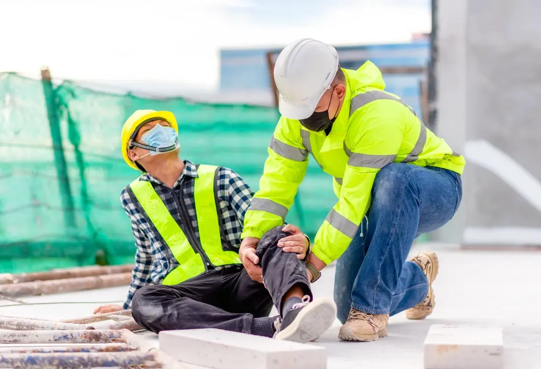 After completing his first aid training on site, a construction worker is administering first aid to his colleague moments after a construction site accident.