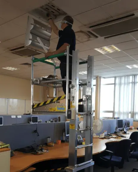 A worker using a desk surfer to check the lights in the office.
