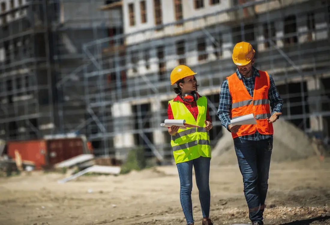Two construction workers conducting height safety investigations on-site, wearing hard hats and high-visibility vests