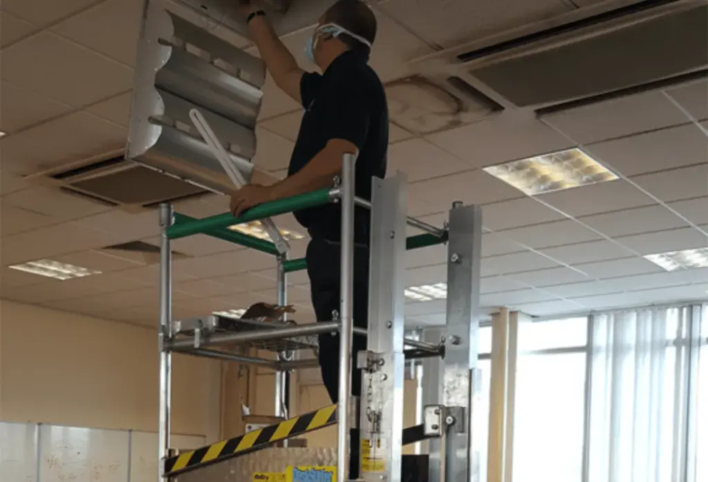 A man using a Desksurfer to inspect ventilation in an office.