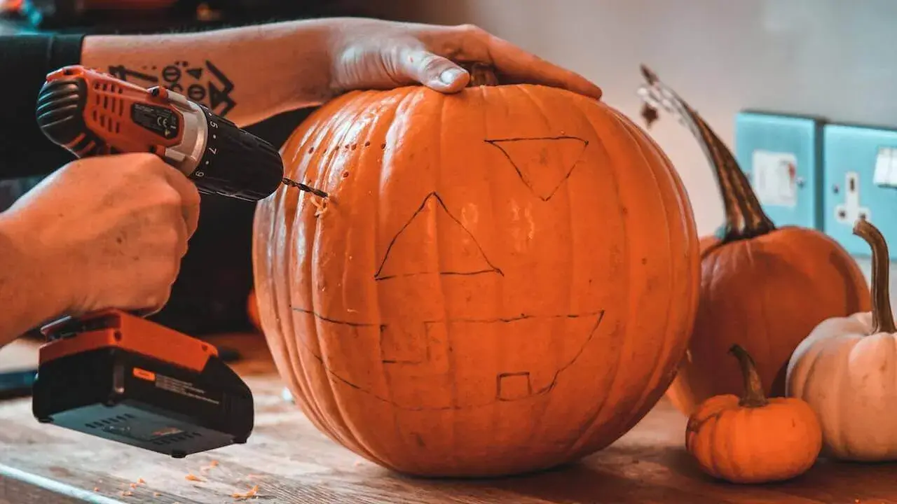 a man unsafely drilling holes into a pumpkin about to have a work-related injury