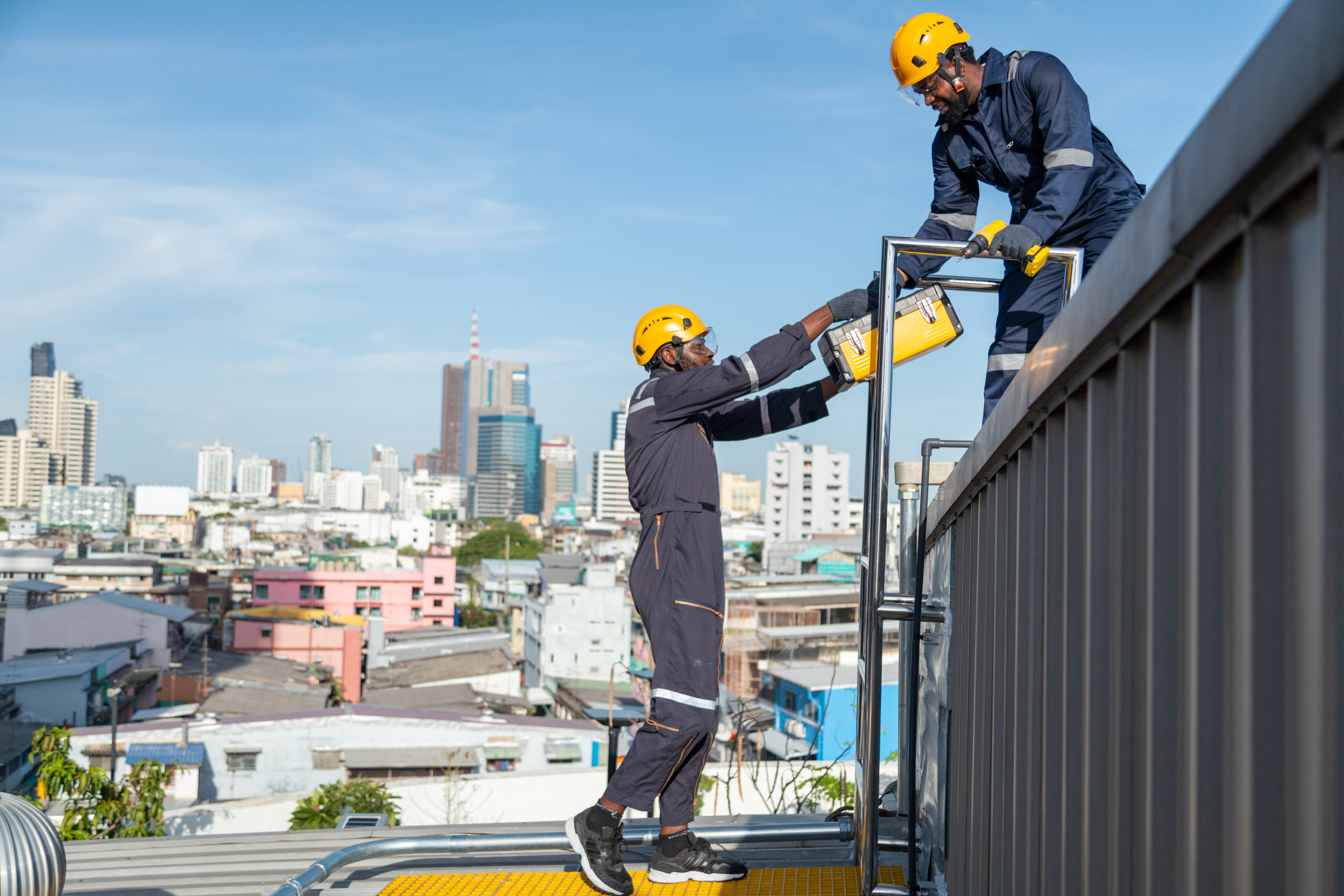 Worker performing Work At Height tasks while wearing safety equipment in a hot outdoor working environment.